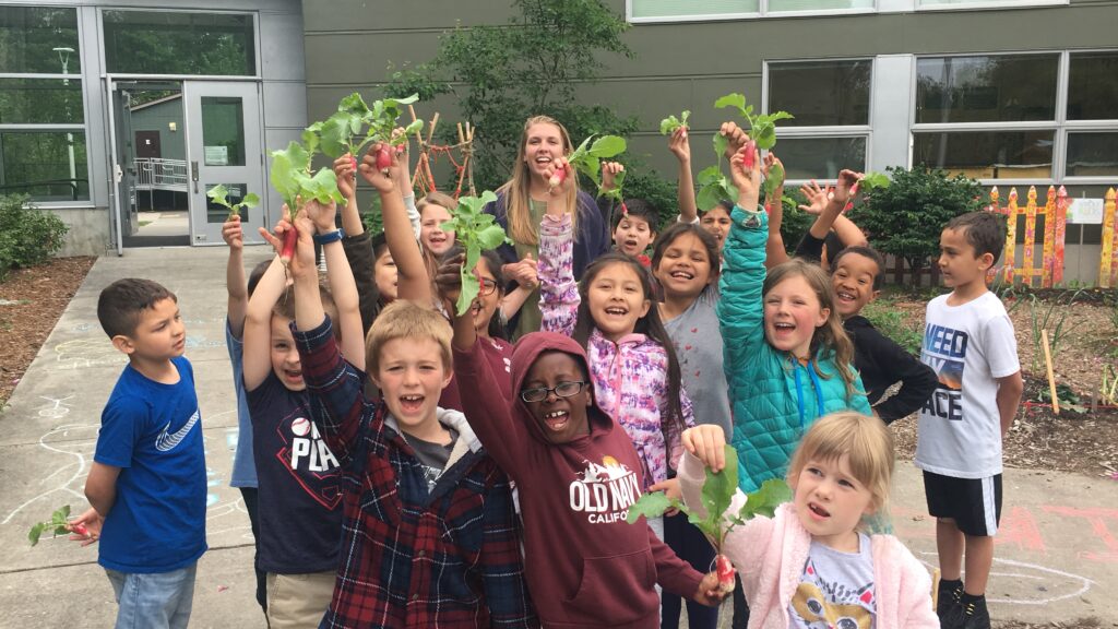 Students stand holding radishes. 