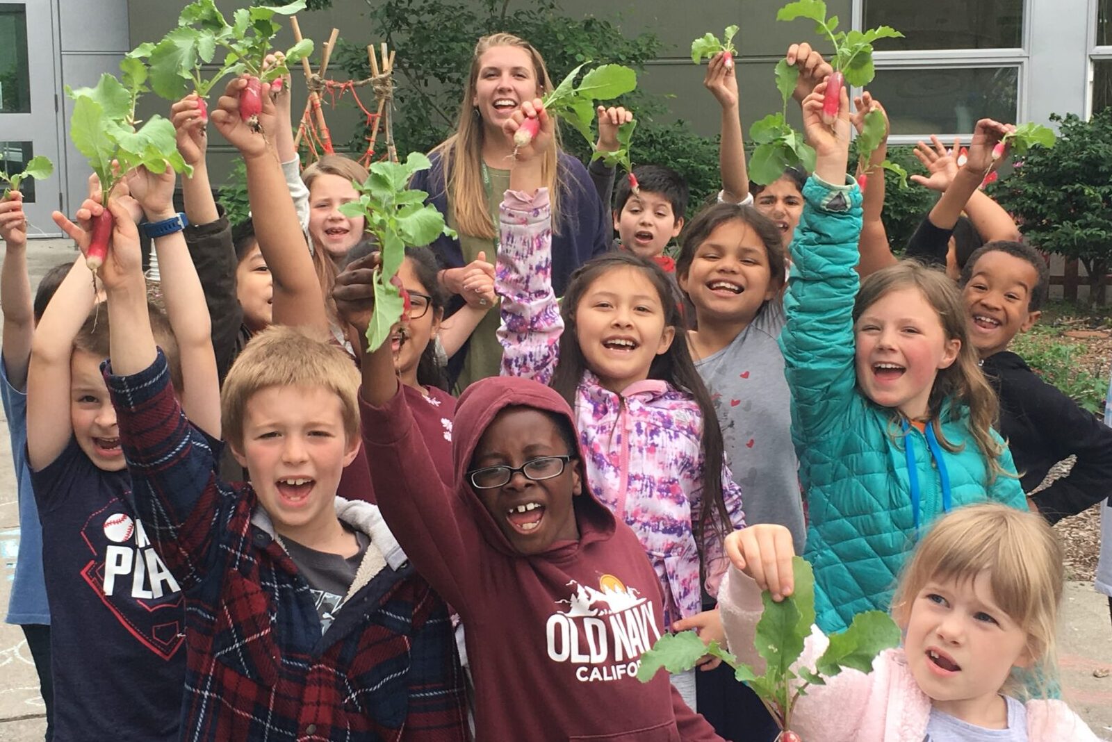 Students stand holding radishes.