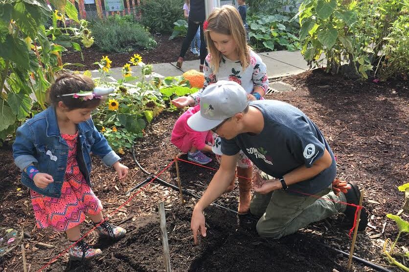 Students stand holding radishes.