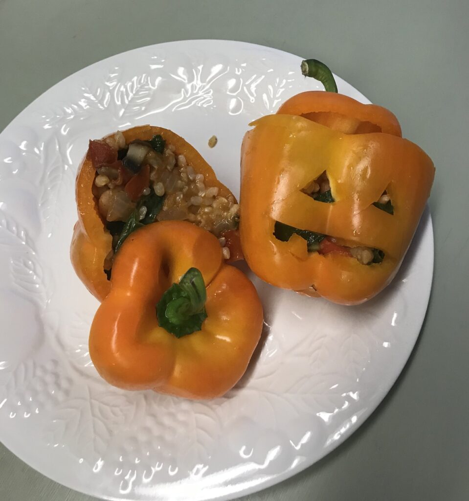 Two jack o lantern stuffed bell peppers on plate