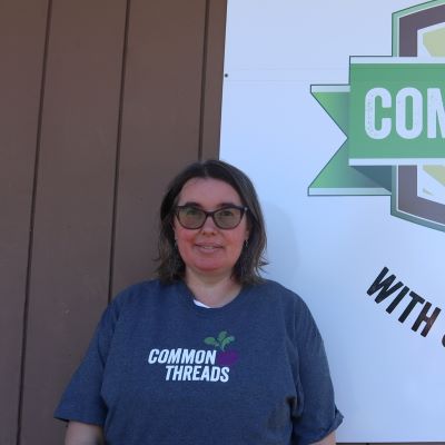Katie Chugg stands in front of the Common Threads logo.