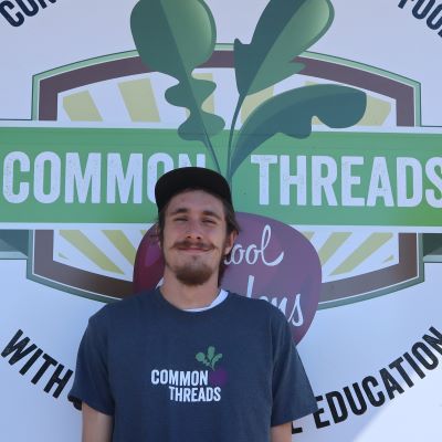 Lyndon Cartwright stands in front of the Common Threads logo.