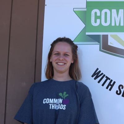Melissa Rijkers stands in front of the Common Threads logo.