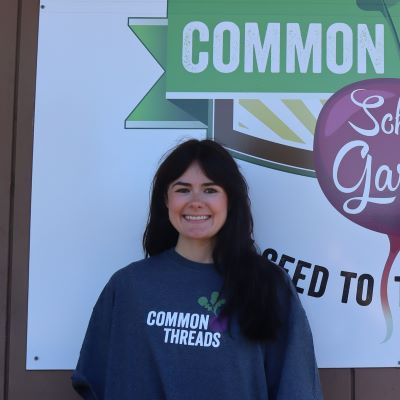 Shyann Young stands in front of the Common Threads logo.