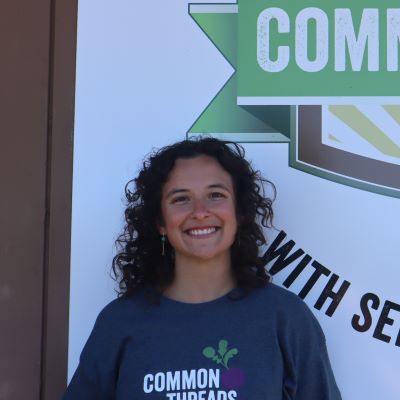 Sidney Perkinson stands in front of the Common Threads logo.