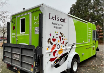 The Common Threads food truck - Green and white with the words "Let's Eat" and an image of vegetable being cooked in a pan.