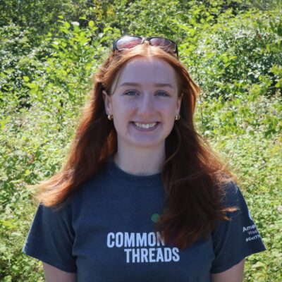 Melissa Rijkers stands in front of the Common Threads logo.