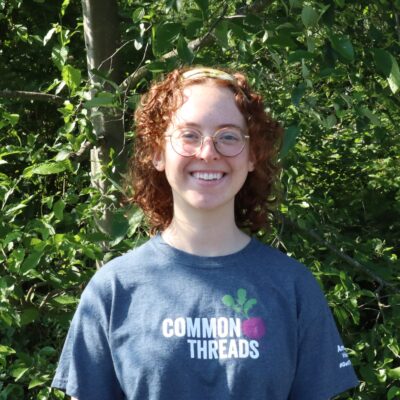 Melissa Rijkers stands in front of the Common Threads logo.