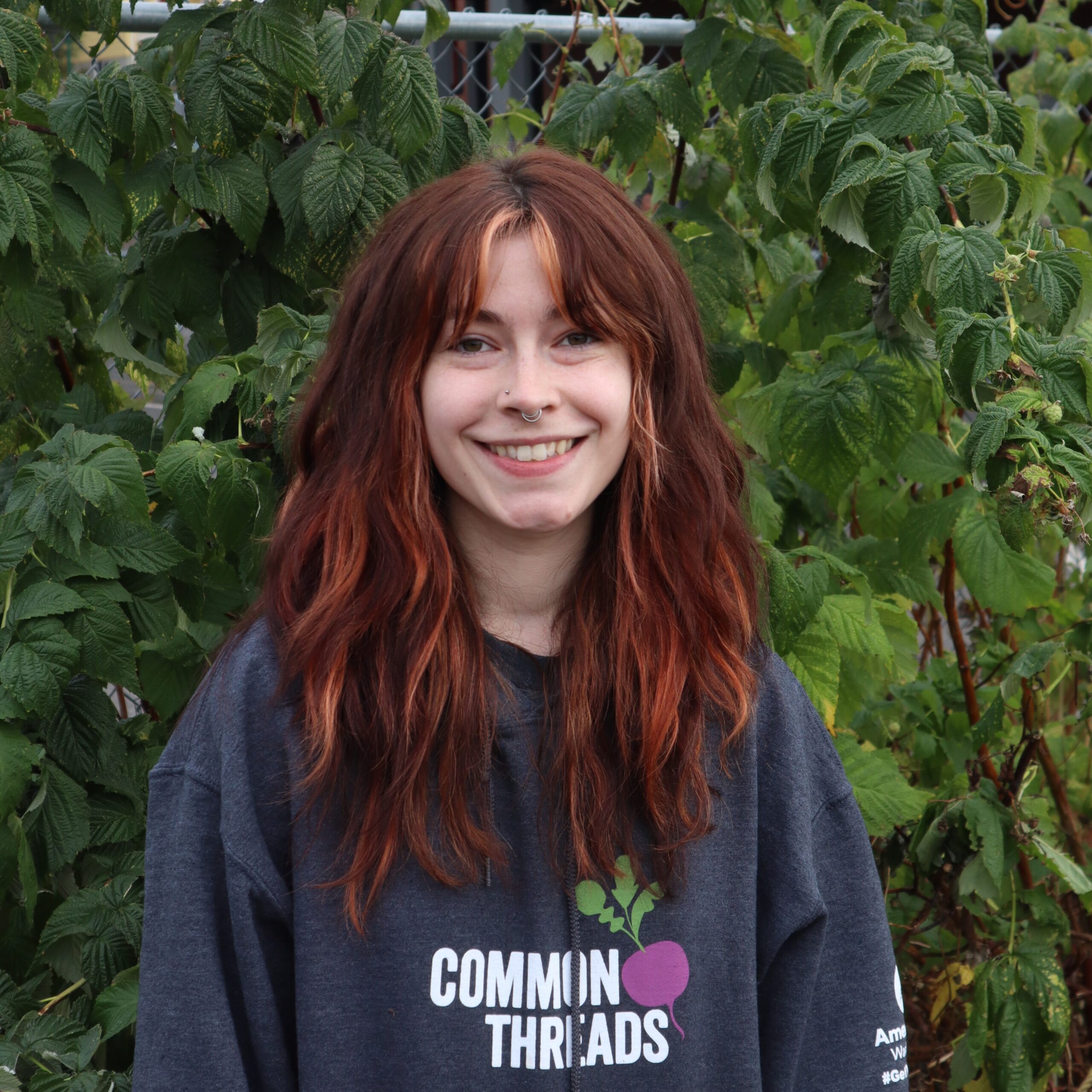 Melissa Rijkers stands in front of the Common Threads logo.